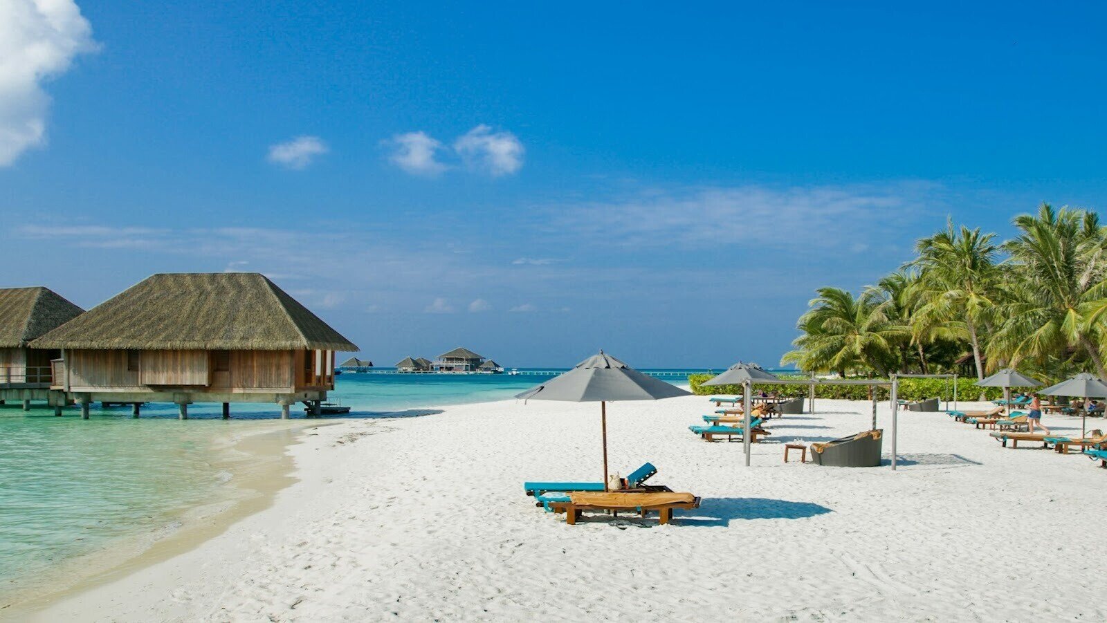 Beach view with blue skies, white sands, trees and umbrellas 