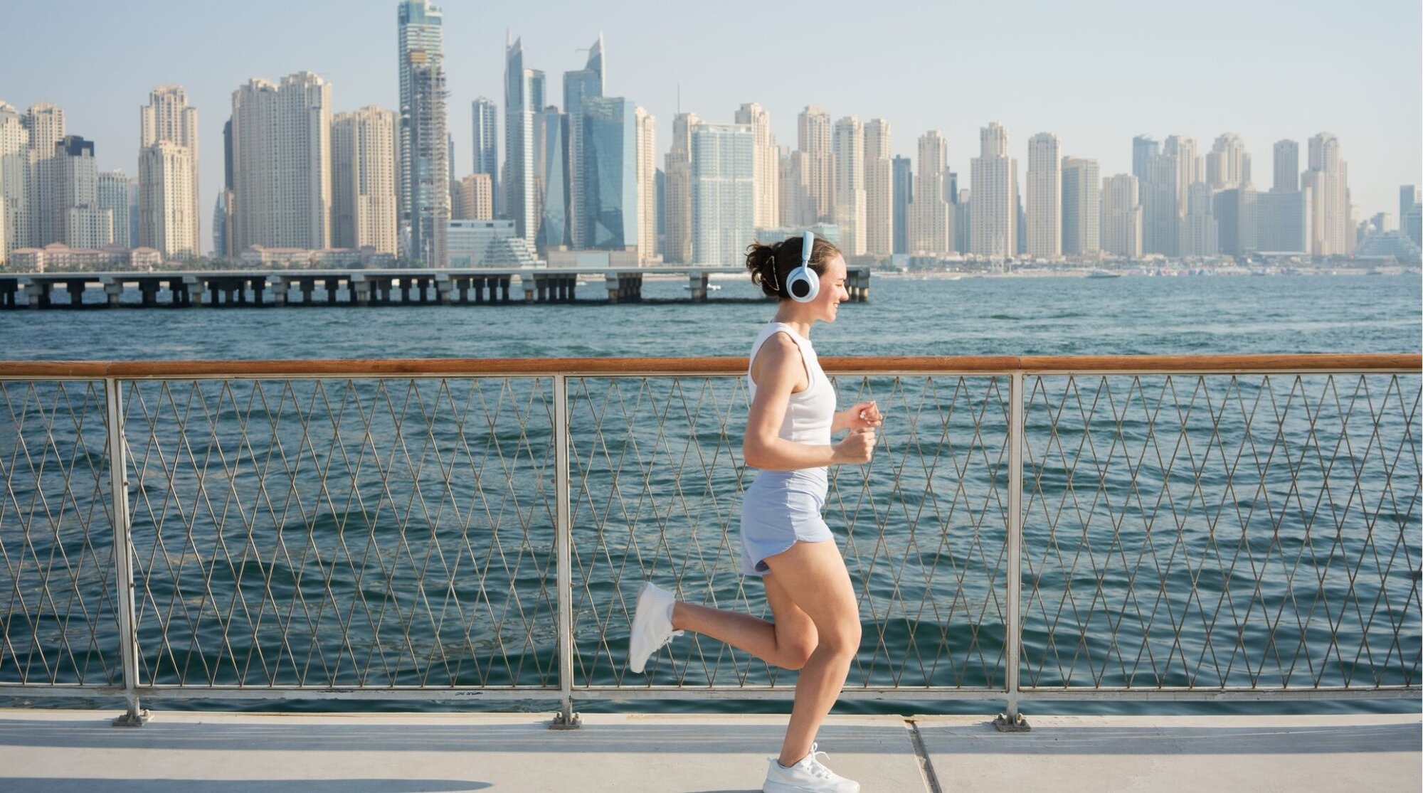 Mulher sorridente e feliz correndo na orla de Dubai.