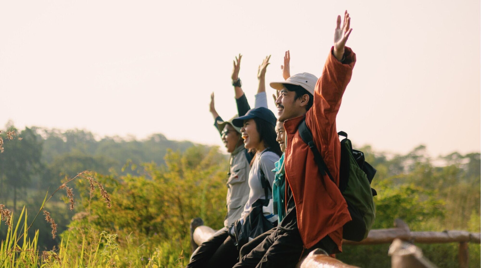 Un grupo de amigos mochileros sonriendo y tomándose una foto en un paisaje asiático.