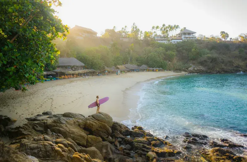 Vista aérea de una playa en Puerto Escondido al atardecer con surfistas en el agua