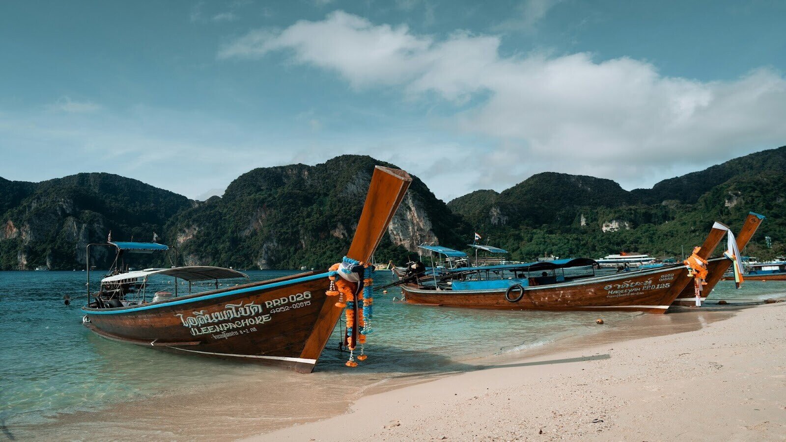 Three boats resting on a beach surrounded by mountains during daytime