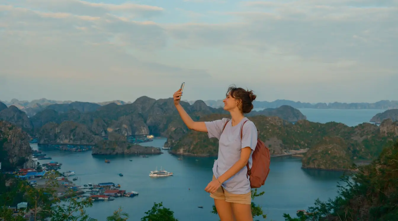 Eine Frau steht auf einem Berg mit Meerblick und nutzt eine App in Vietnam 