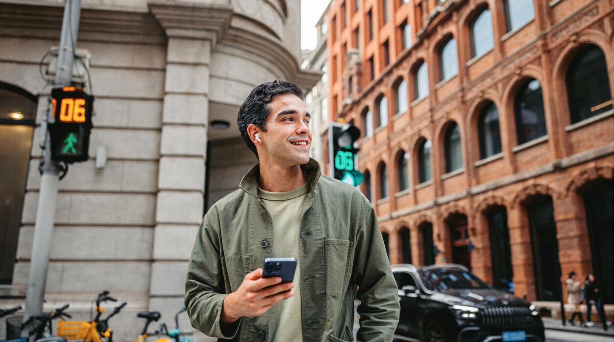 Joven usando el móvil con auriculares en la calle; usar eSIM y SIM física a la vez (Dual SIM).