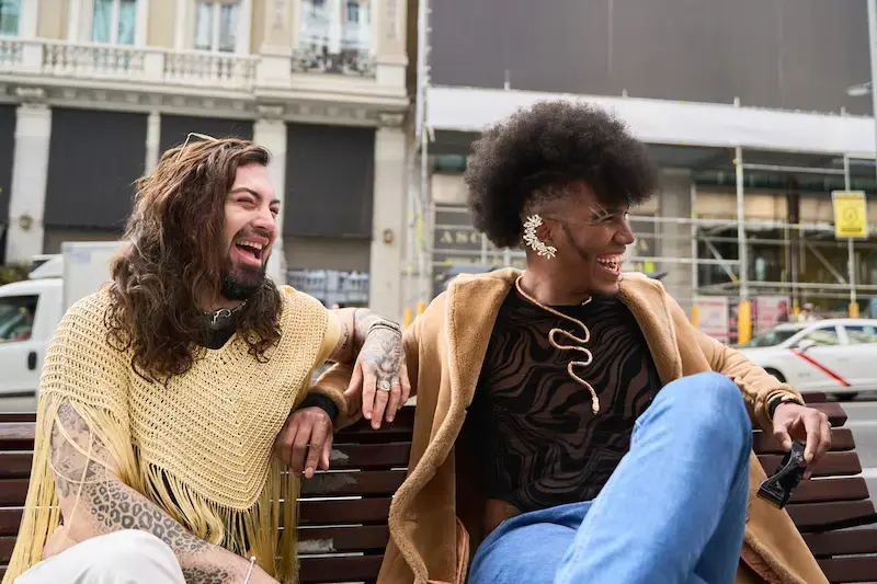 Pareja local riendo en una banca en Barcelona.