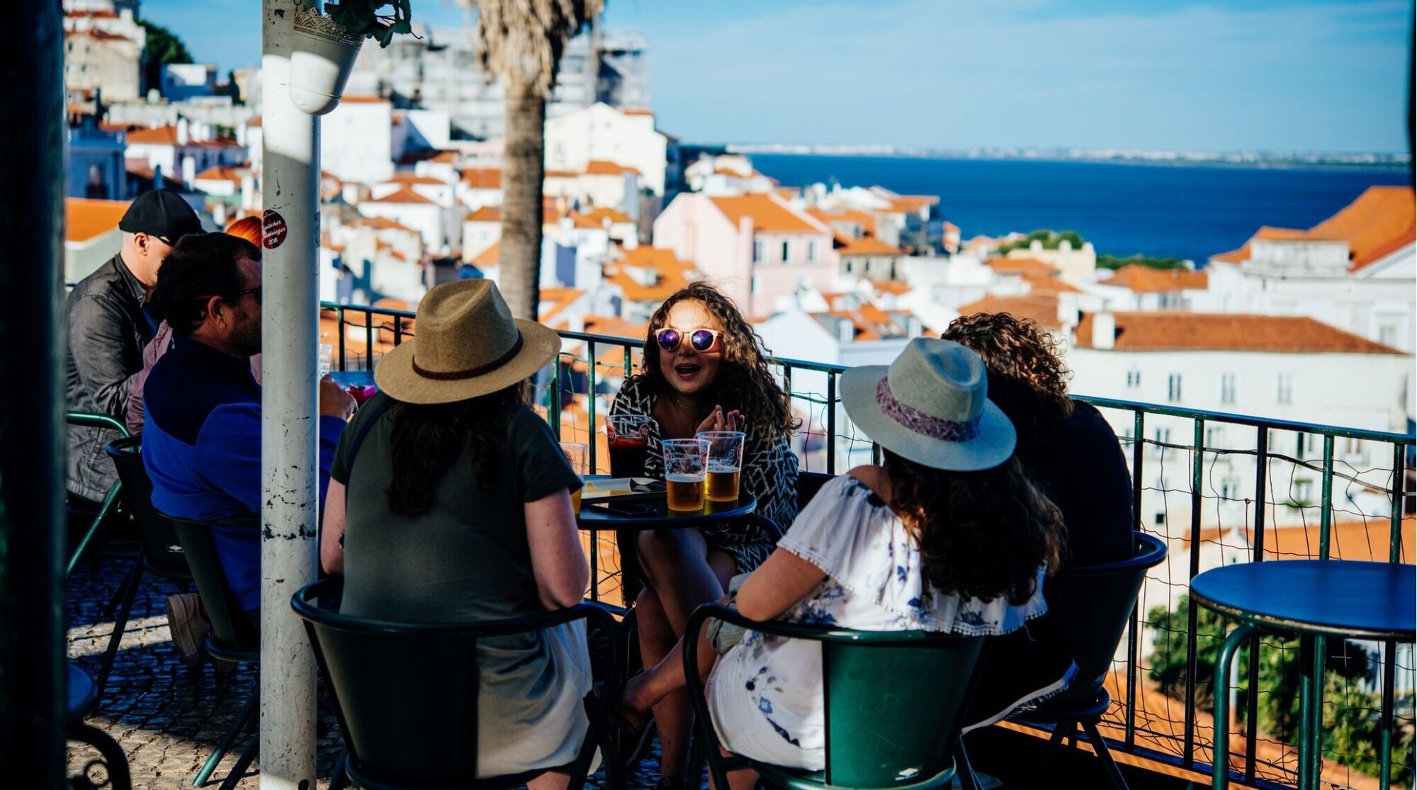 Jovens sentados a mesa em um miradouro em Lisboa.