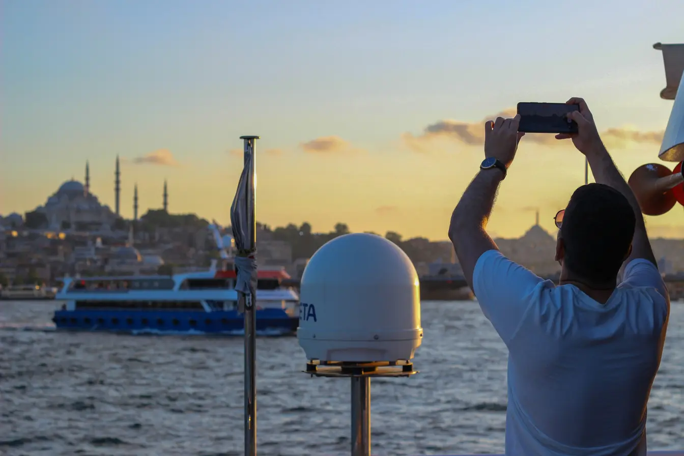 Imagen de una persona haciendo una foto con su móvil desde la cubierta de un barco para reflejar las cosas que hacer en Estambul.