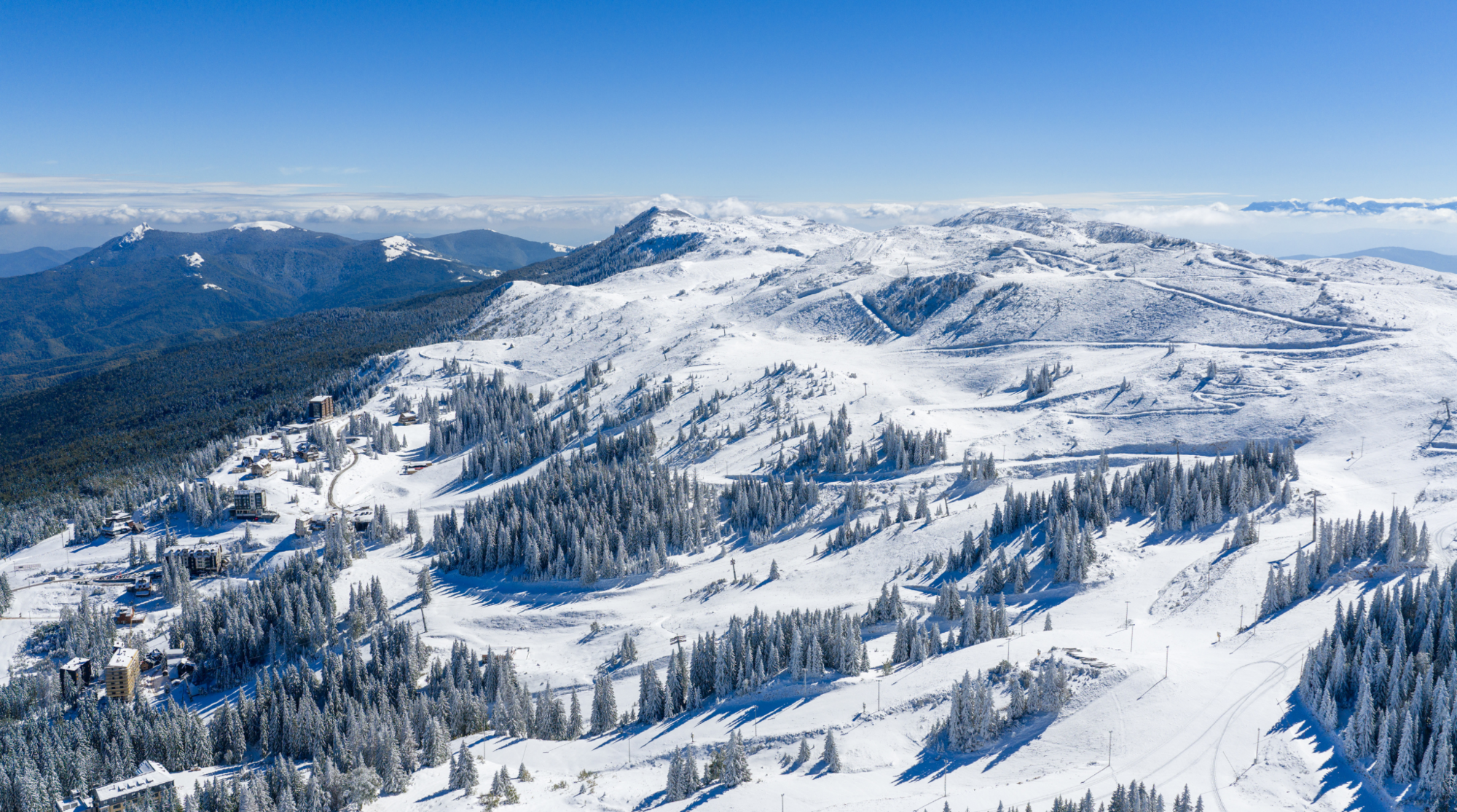 Veduta aerea delle piste innevate di Jahorina in Bosnia ed Erzegovina, circondate da foreste, destinazione ideale per sciare in Europa low cost.