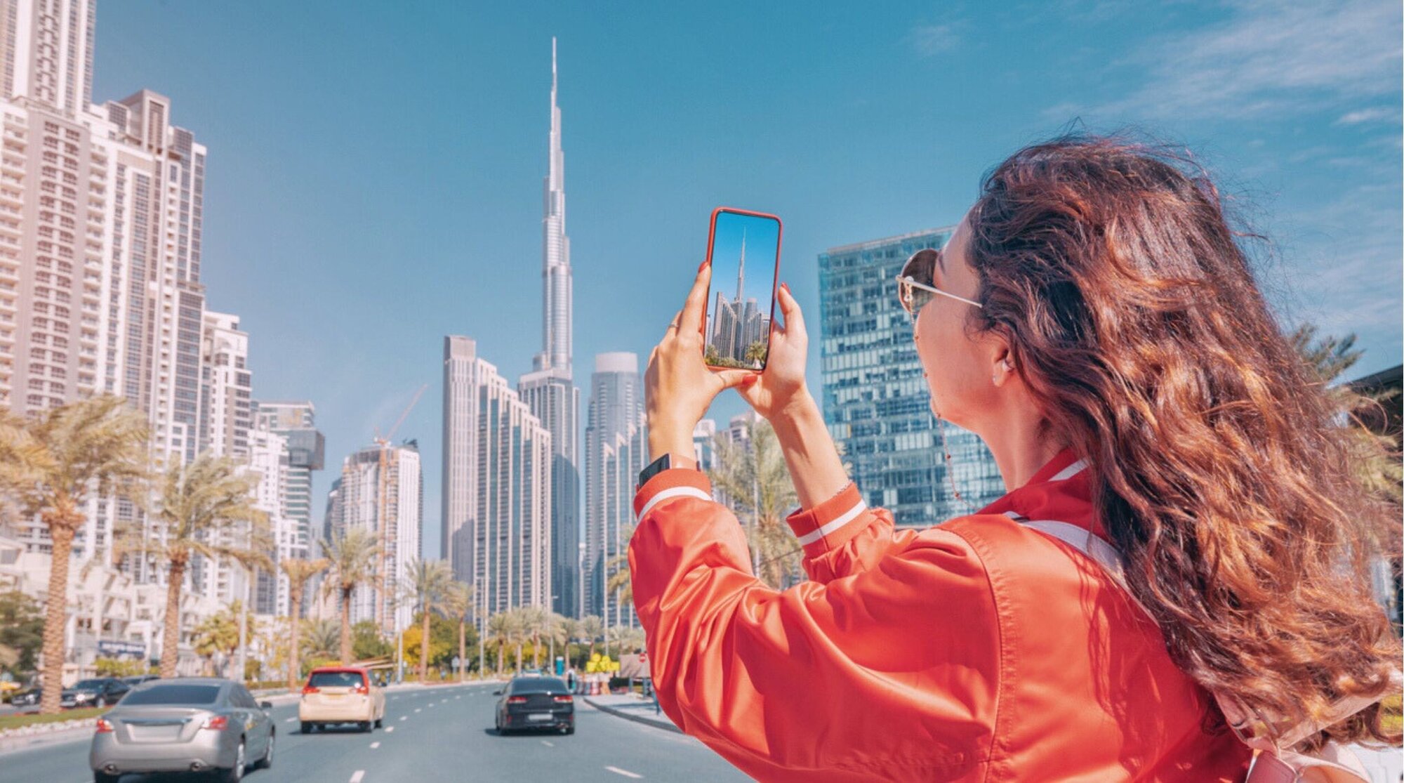 Una chica tomando fotos del Burj Khalifa en Dubái con su teléfono.
