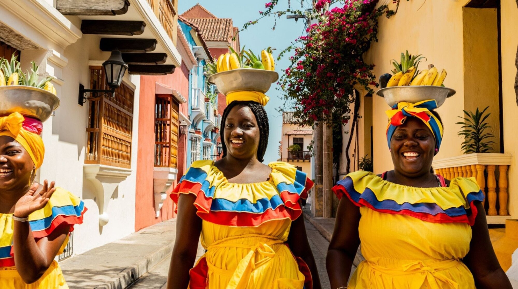 Vendedoras palenqueras con vestidos coloridos caminando por una calle de Cartagena, Colombia.