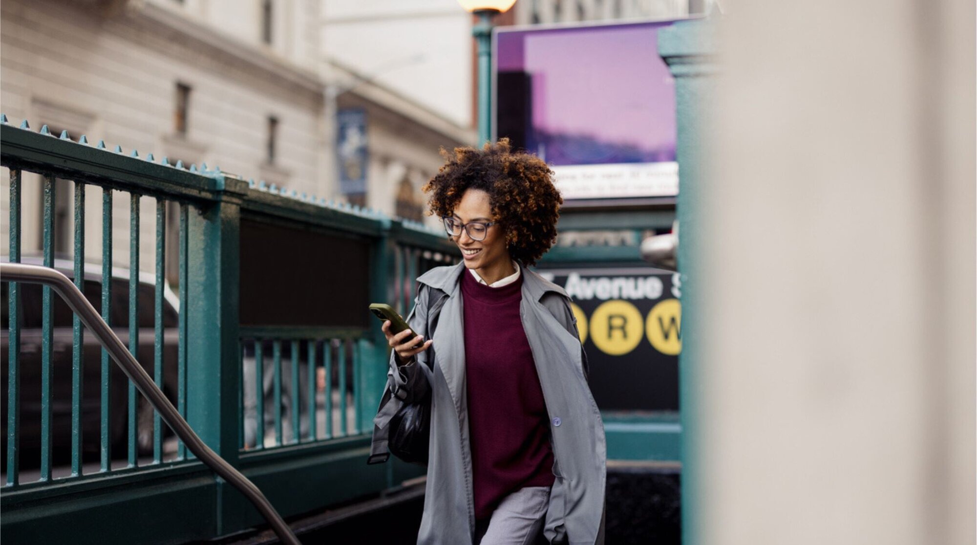 Mulher usando celular na saída de metrô em Manhattan