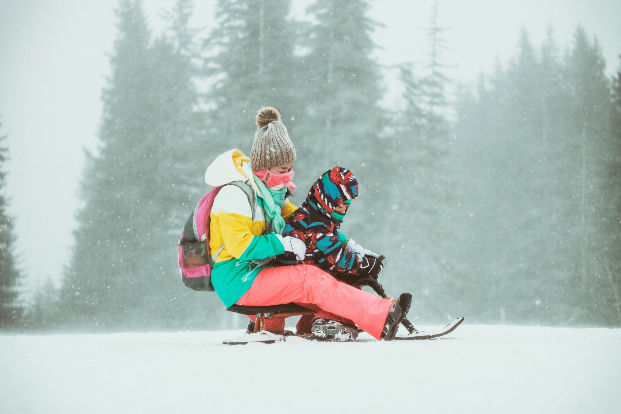 Person wearing a colorful outfit with a child on a family ski trip