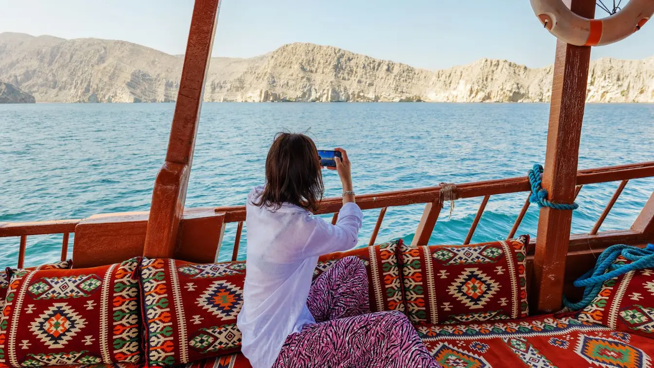 Voyageuse prenant des photos depuis un boutre touristique dans les fjords d’Oman.