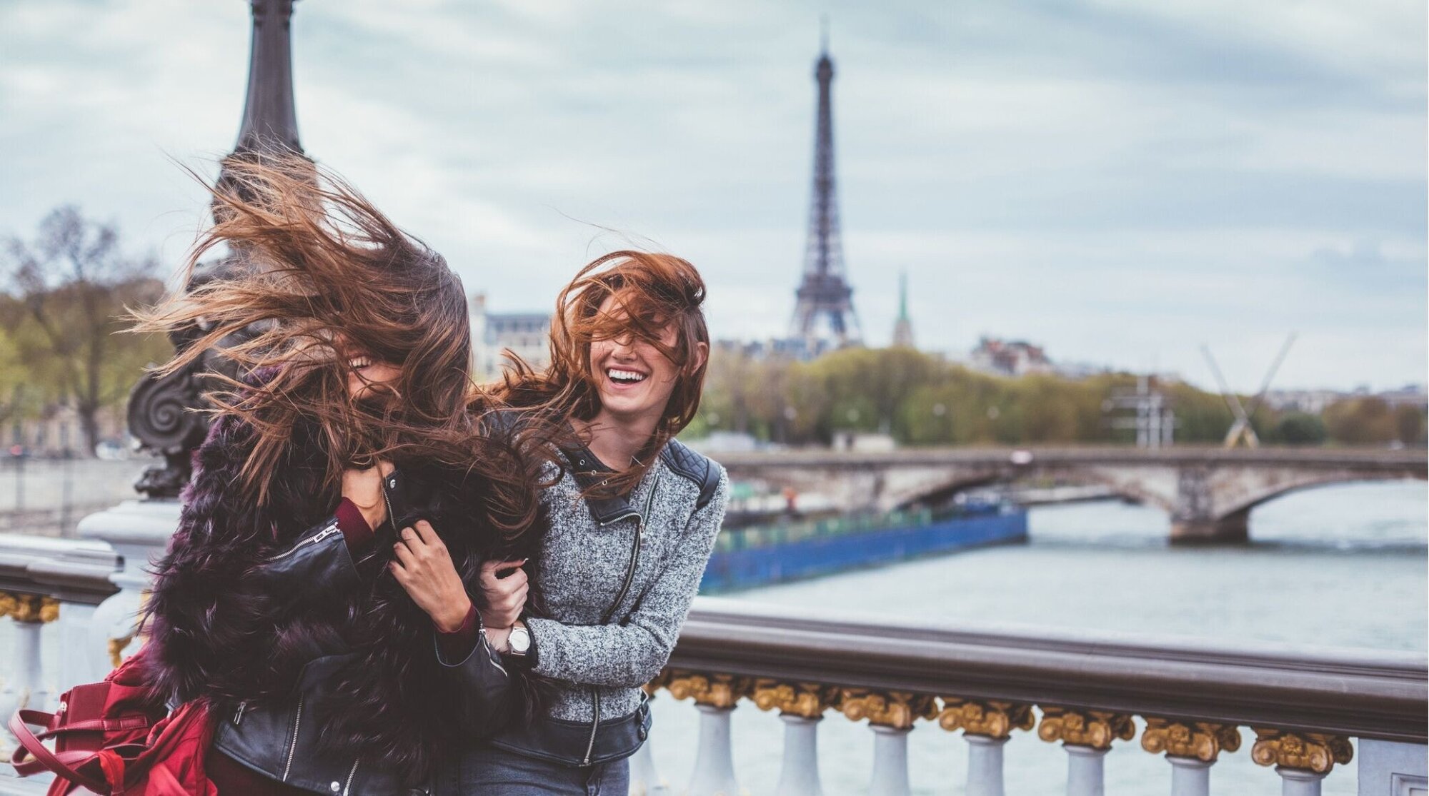 Amigas con el cabello despeinado por el viento durante un día frío en París en invierno.