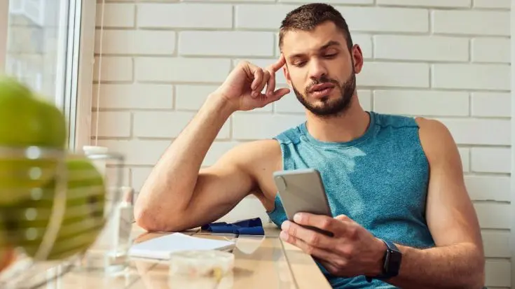  Um jovem está sentado em um café olhando para o smartphone.
