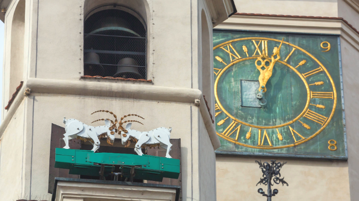 The mechanical goats on Poznan, Poland's Town Hall clock at noon - two white goats made out of wood, butting horns when the clock strikes. The clock face is green and the numbers and ands are gold. To illustrate a blog entitled Extreme Day trips to Europe from London.