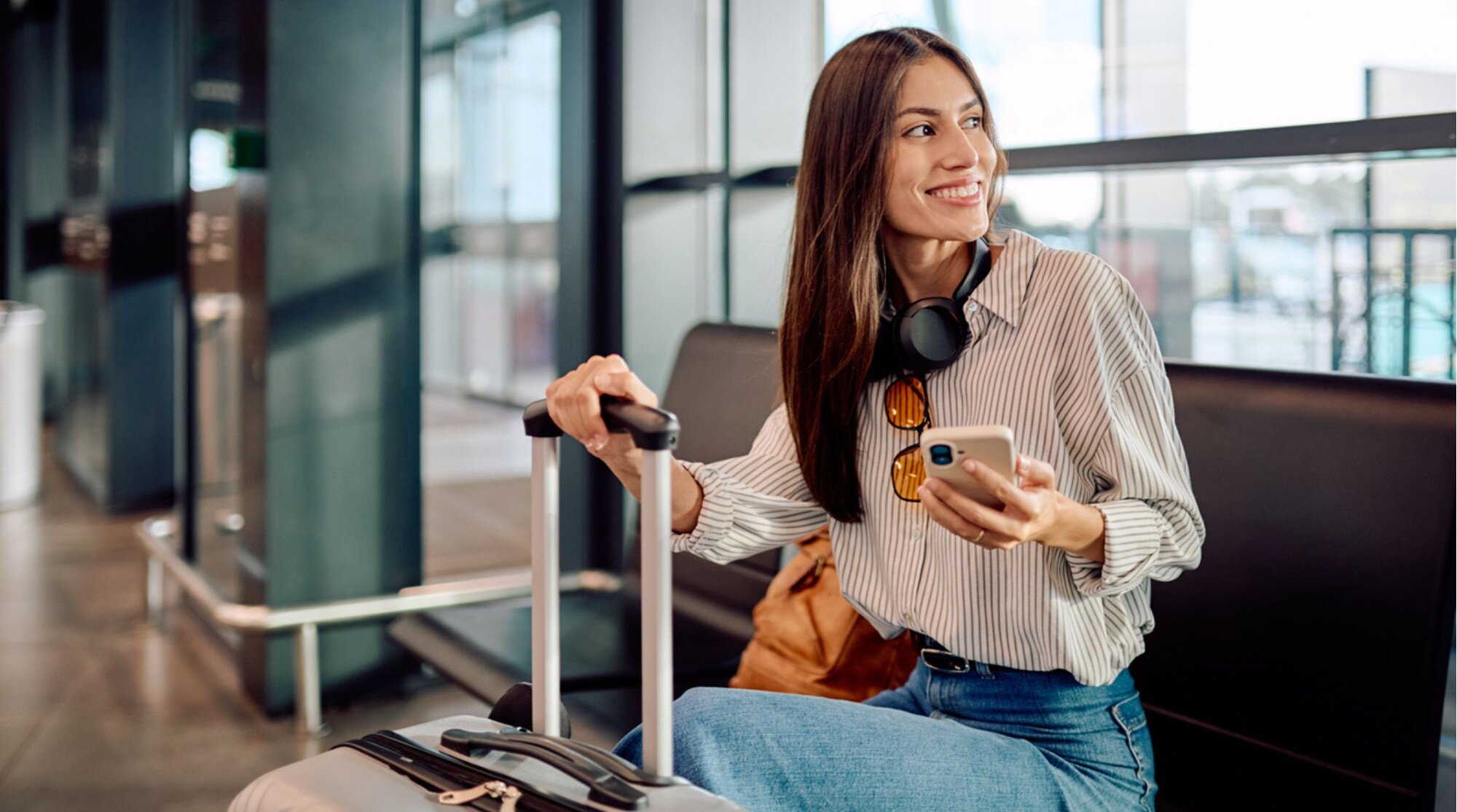 Voyageuse utilisant son téléphone à l’aéroport avant son départ en Grèce