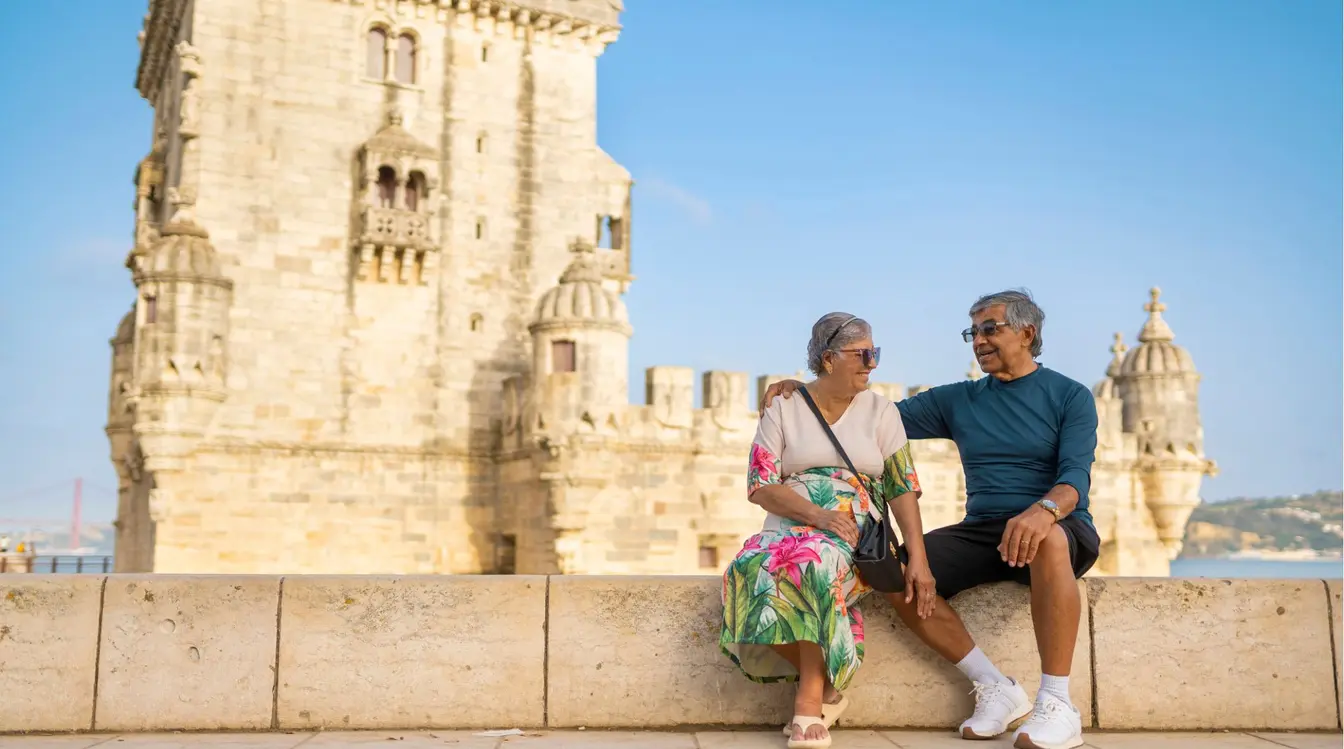 Casal de viajantes maduro posando para fotos na Torre de Belém, um dos principais pontos turísticos de Lisboa.