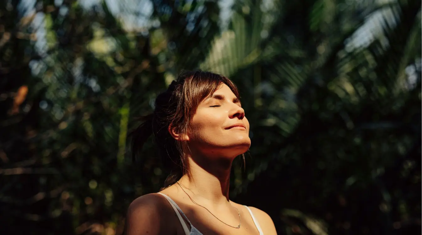 Femme souriante profitant du soleil pendant un moment seule en voyage.