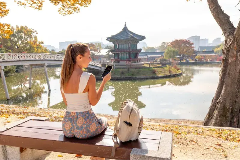 ソウルの秋の景福宮でスマートフォンを使う女性旅行者