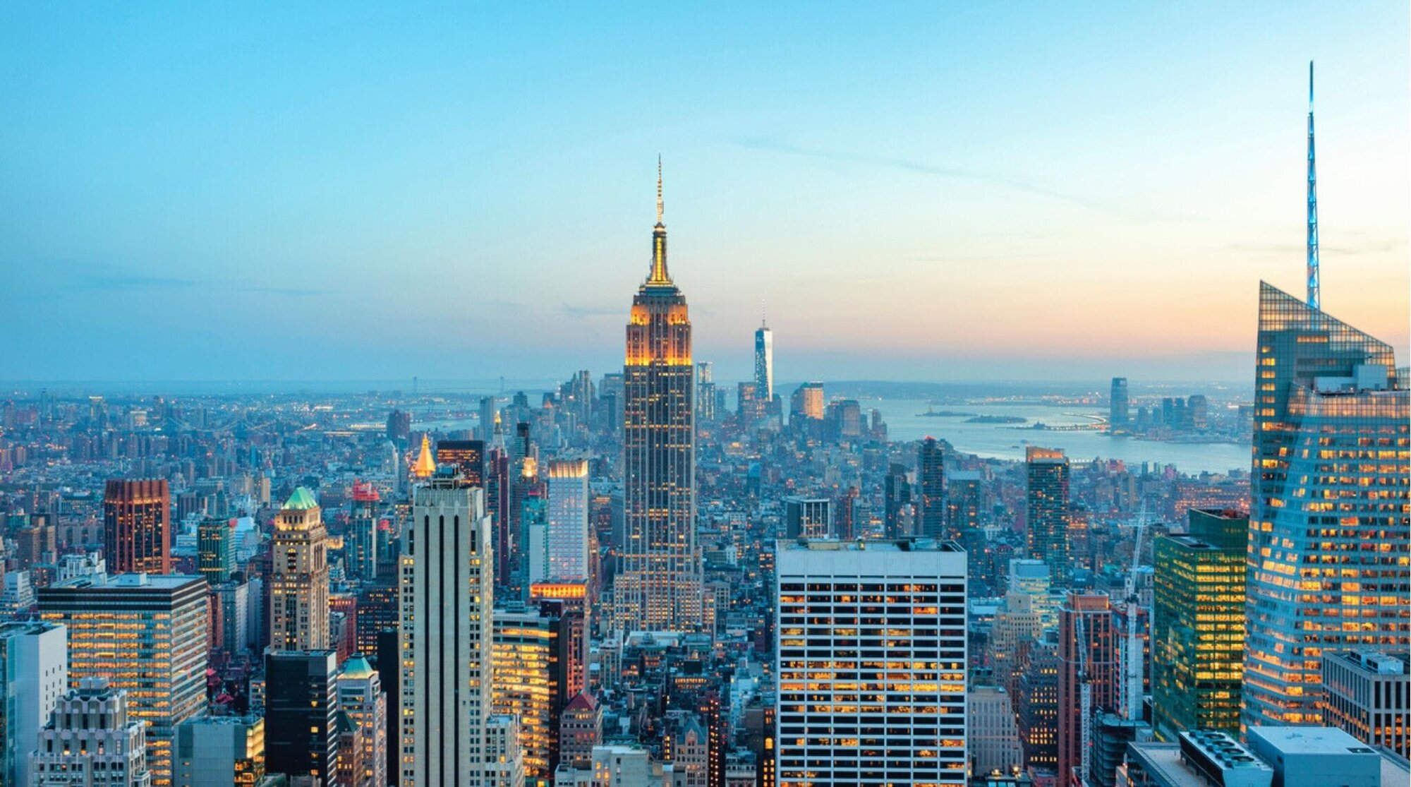 Vista panorámica de los rascacielos de Manhattan iluminados al atardecer, una imagen emblemática de Nueva York.
