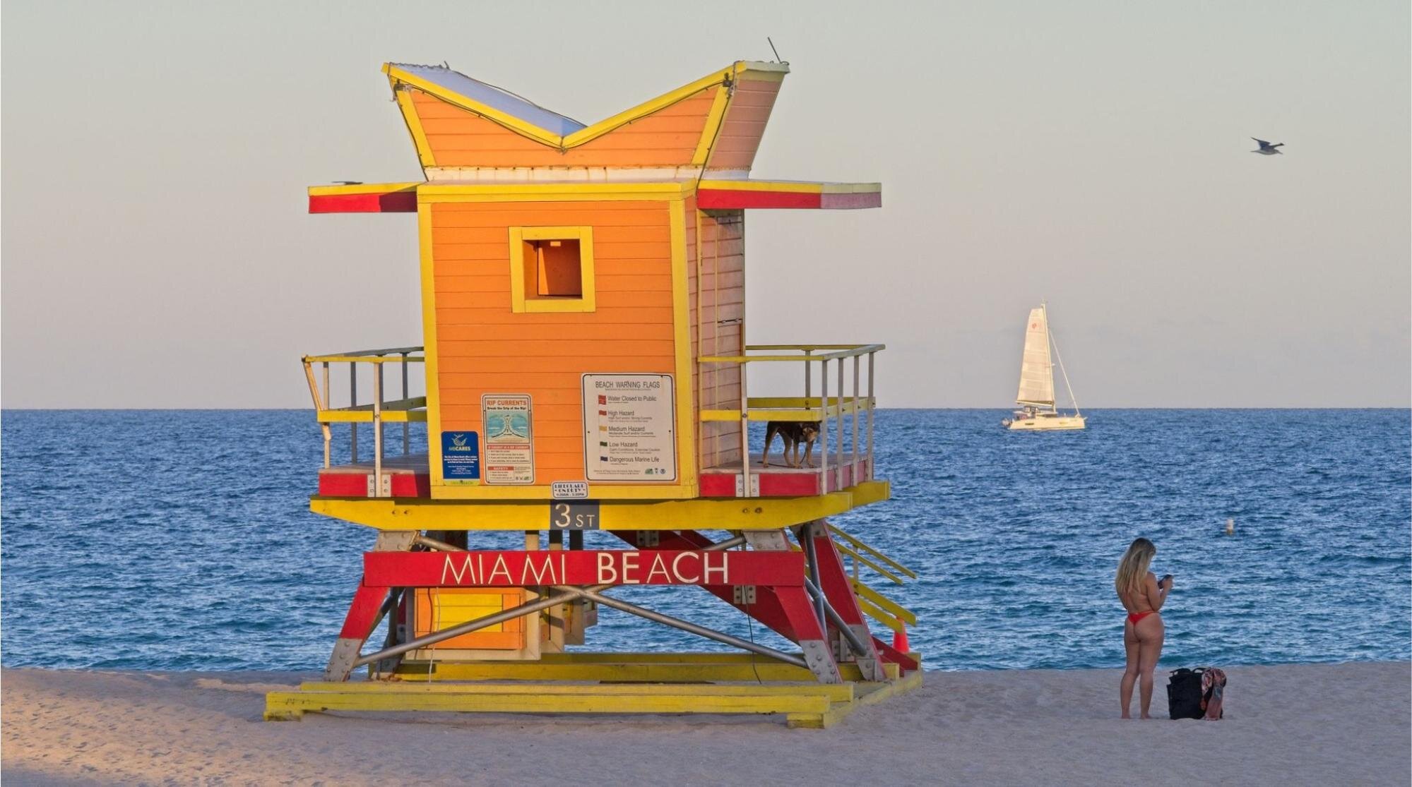 Cabana colorida de salva-vidas de Miami Beach na praia do sul no final do dia, com clima agradável, céu claro e mar azul vibrante.
