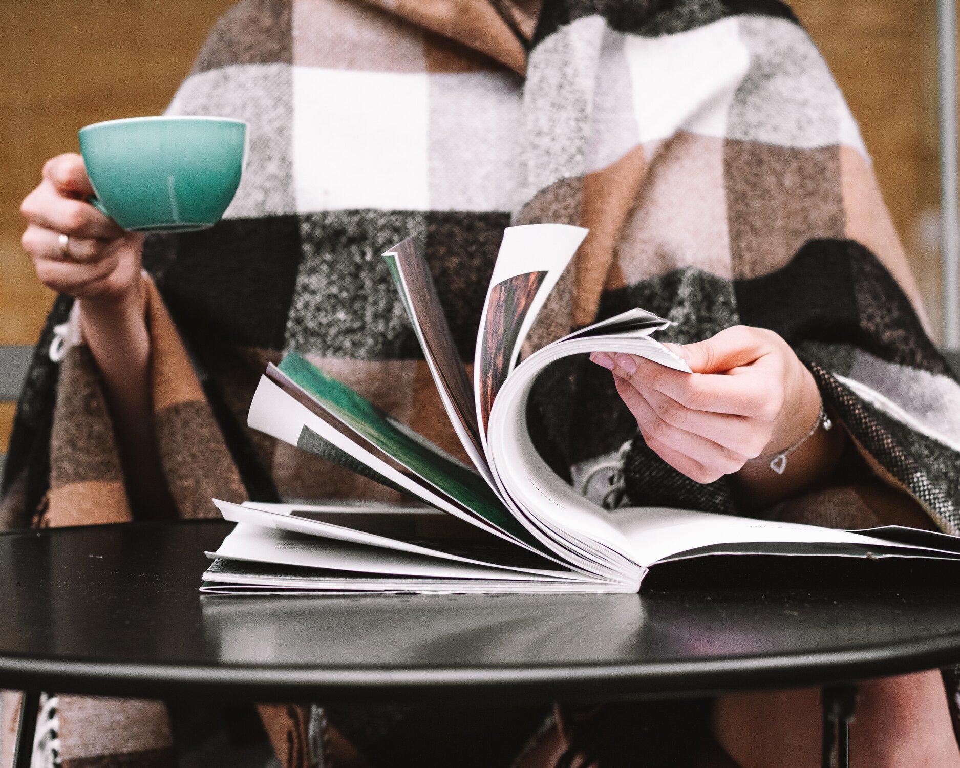 Woman with a cup of coffee flipping through a photo book