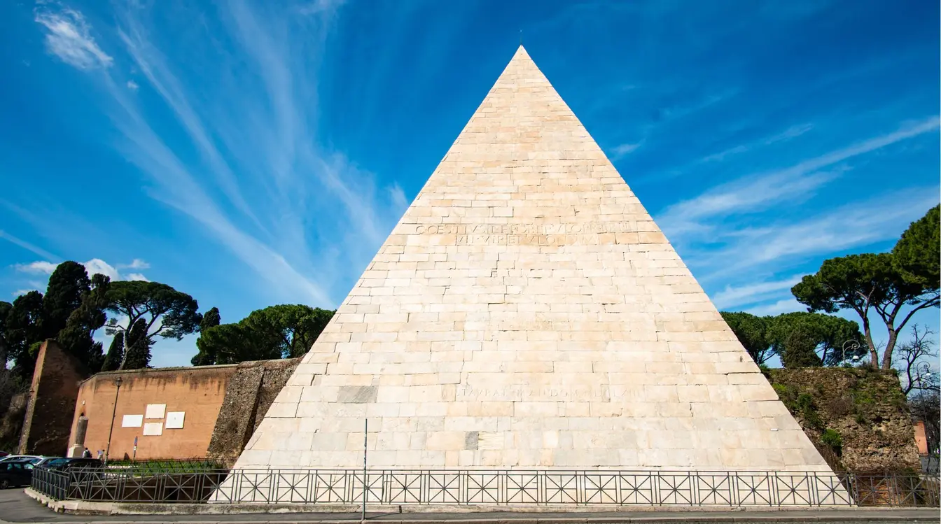 Front view of the white marble exterior of the Pyramid of Cestius in Rome.