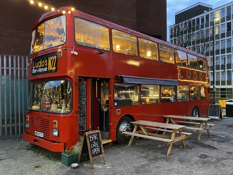 A vintage red London double-decker bus serving as a cozy pub.
