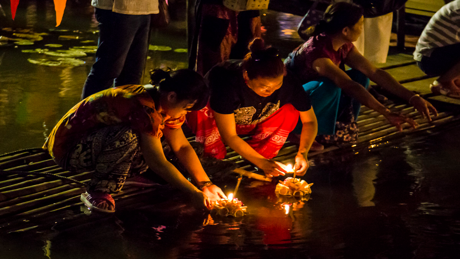 People releasing lanterns on water at night