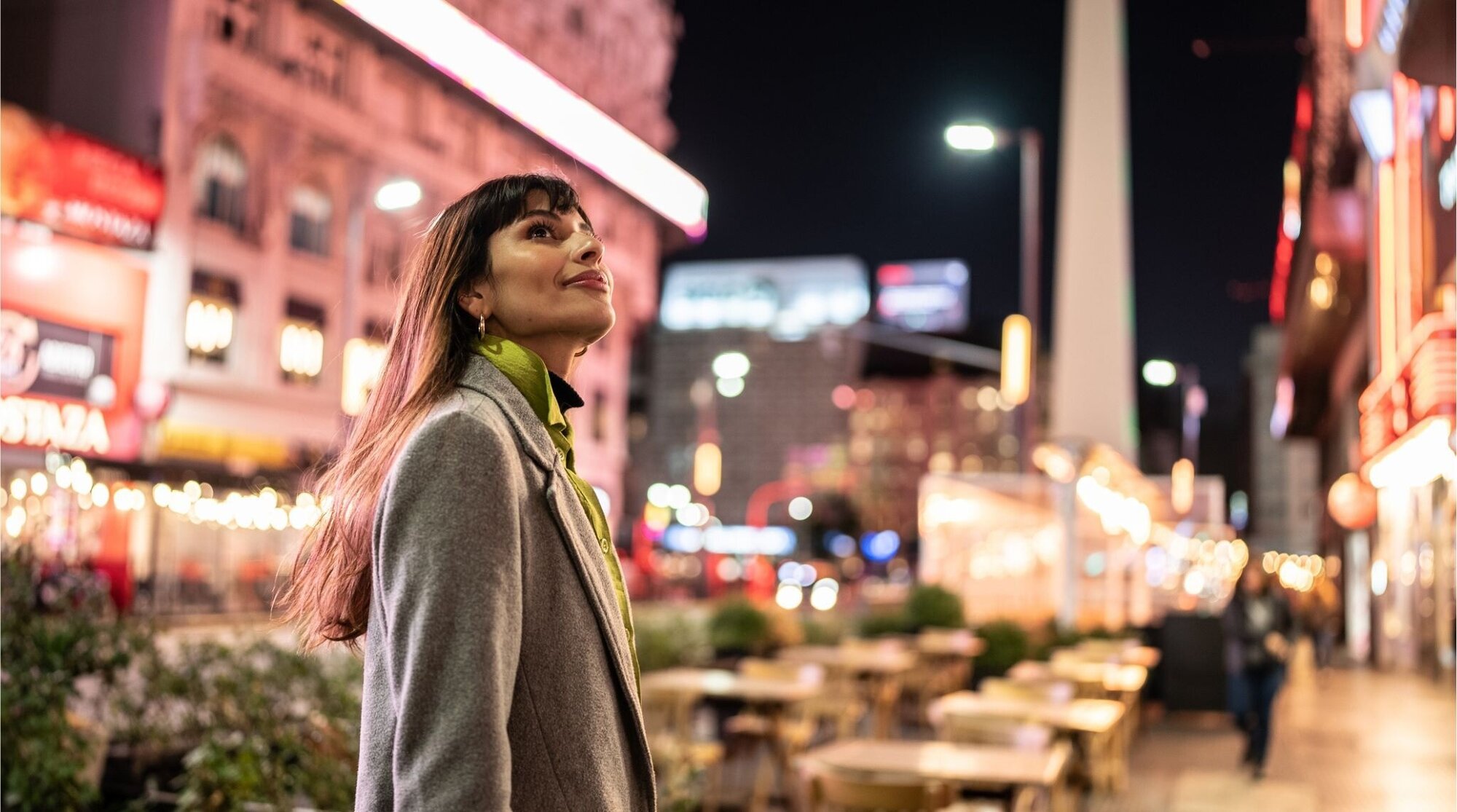 jovem contemplando luzes da cidade à noite.