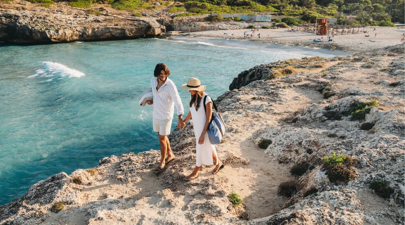 Touristes marchant sur un sentier en falaise au-dessus d'une crique de Majorque, dans les îles Baléares.