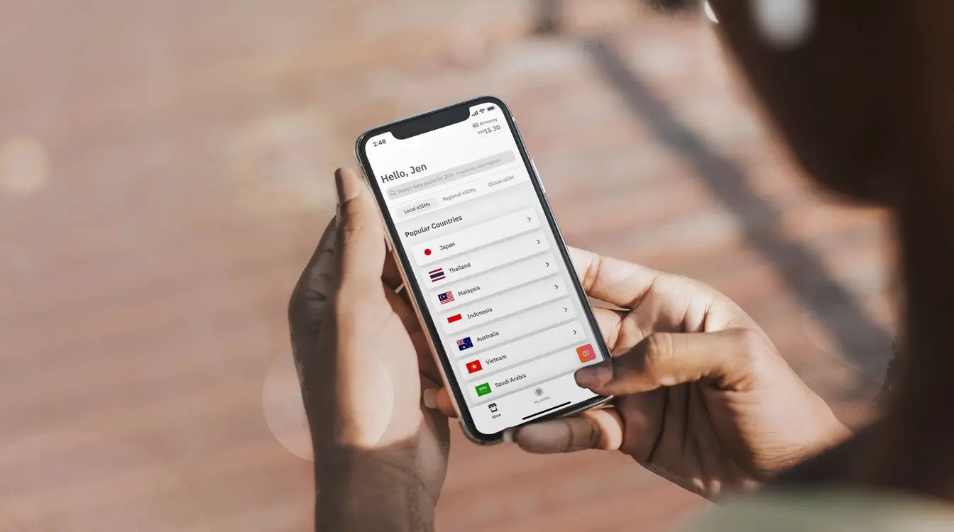 Una persona sostiene su teléfono mostrando la pantalla de la app de Airalo con la lista de países disponibles para comprar una eSIM.