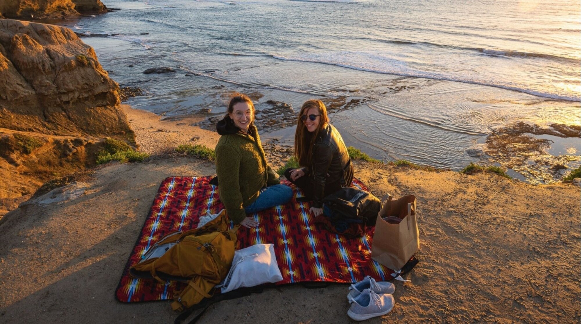 Dos viajeras haciendo picnic sobre los acantilados en Sunset Cliffs, San Diego.