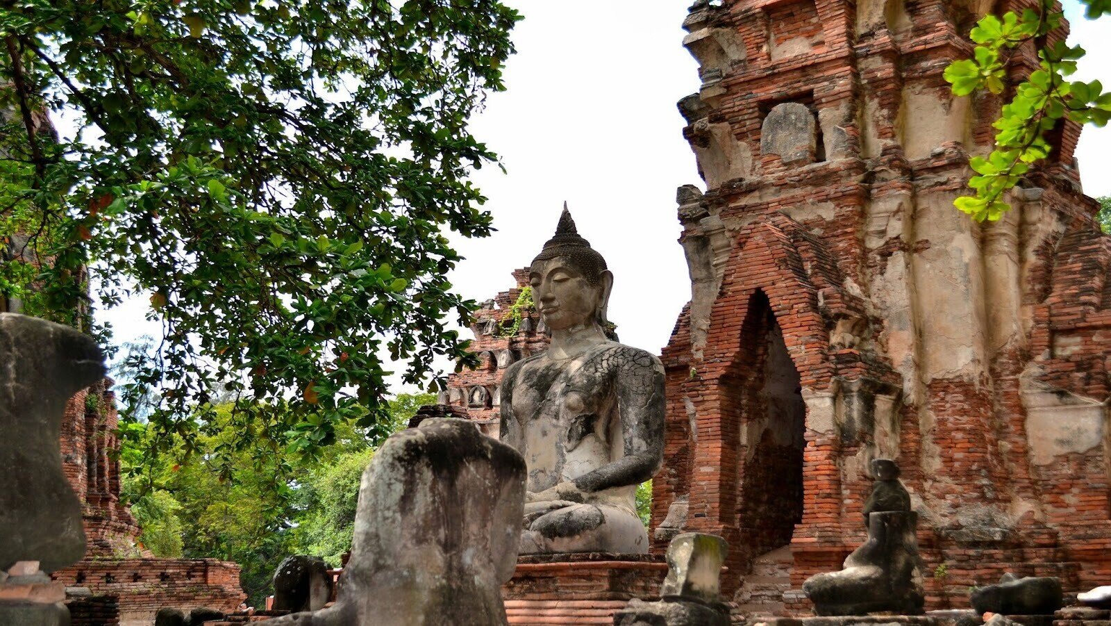 Historic brick building with a tree and a statue of Buddha beside it