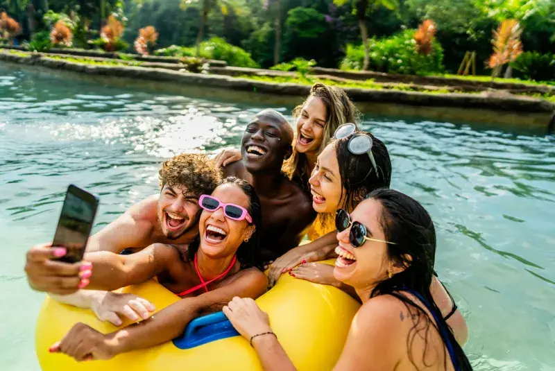 Grupo de amigos en un flotador en el agua tomándose una selfie con un smartphone.