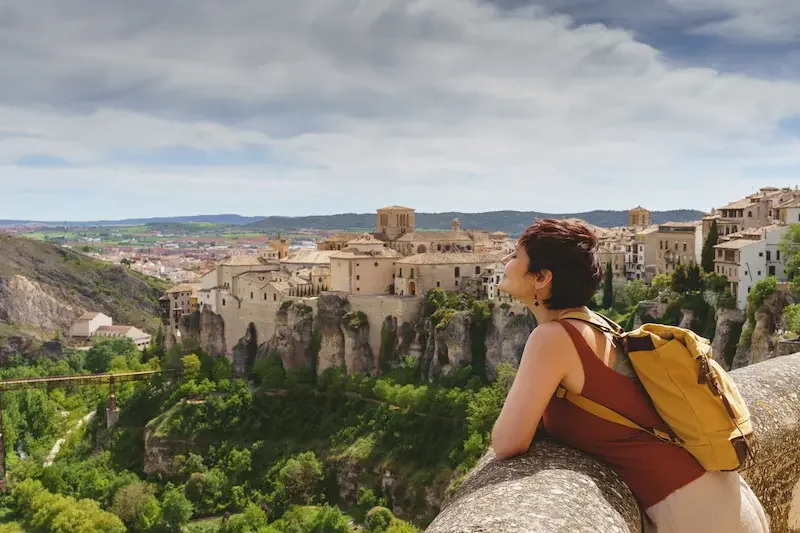 Viajera disfrutando de la vista de una ciudad histórica en España desde un mirador.
