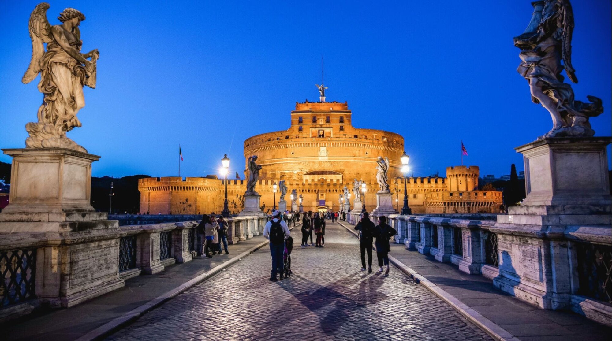 As luzes da noite iluminam a majestosa cena do Castel Sant'Angelo e sua ponte.