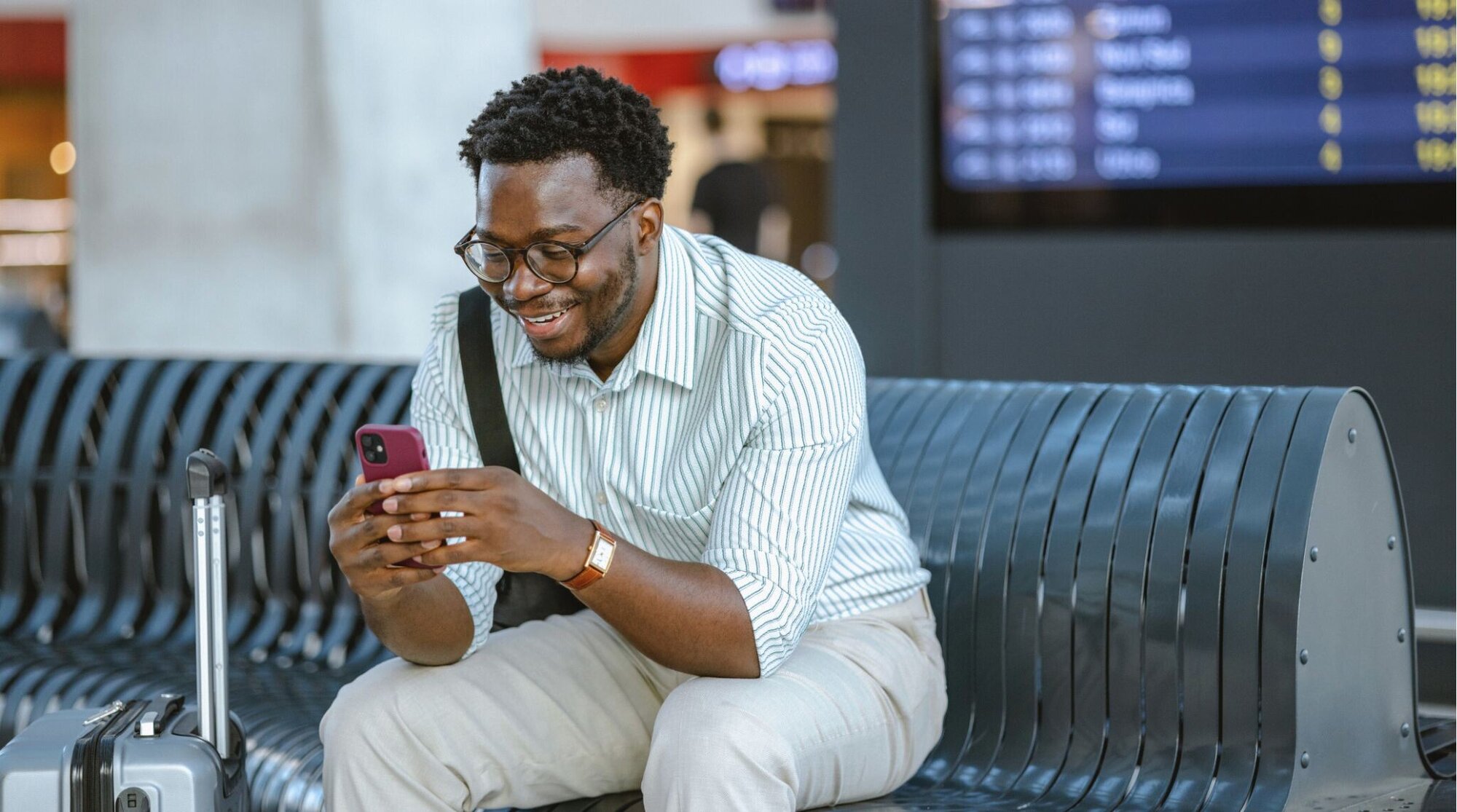 Homem no aeroporto de Guarulhos utilizando chip internacional no celular enquanto aguarda voo