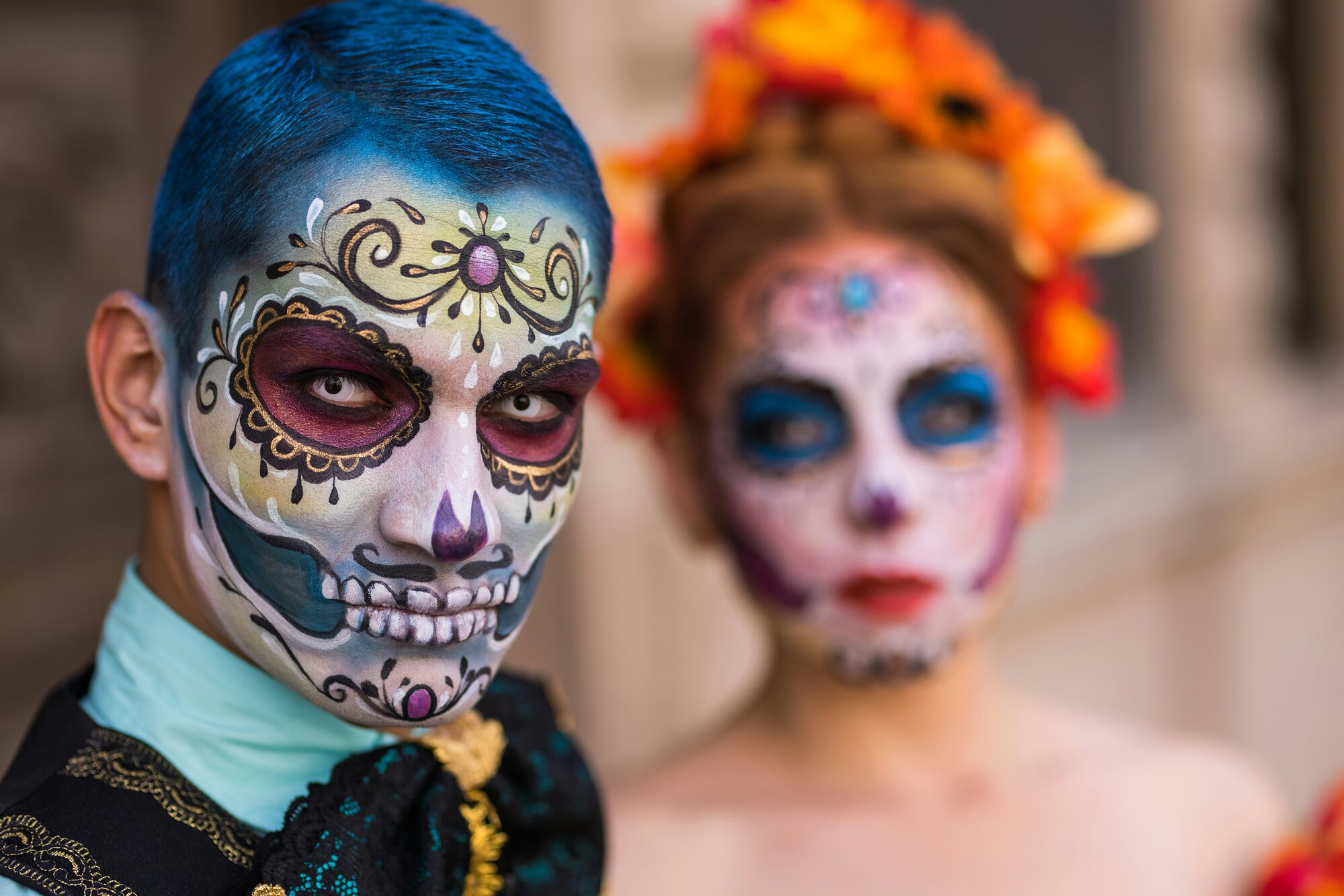 Imagen en primer plano de dos personas con maquillaje artístico de catrinas y catrines típico del Día de Muertos en Oaxaca