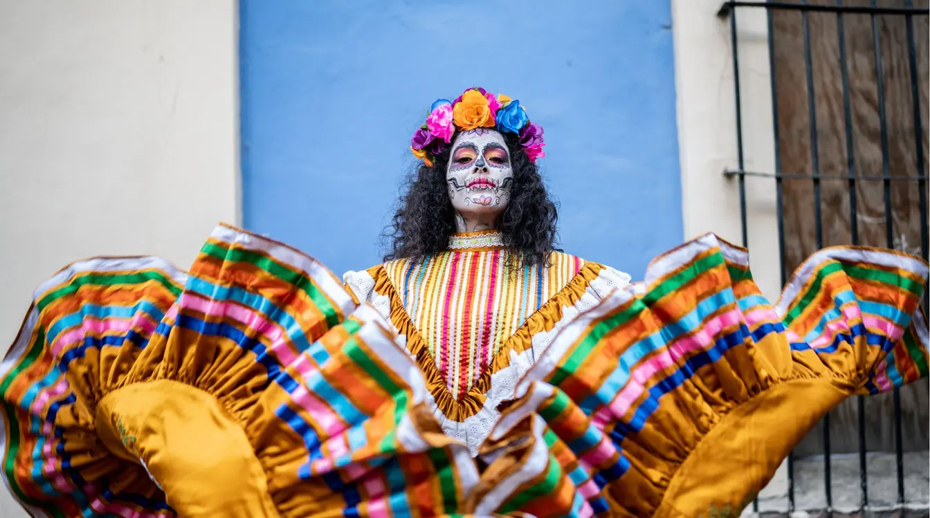 Femme vêtue d’une tenue colorée et maquillée en Catrina pour le Día de los Muertos au Mexique.