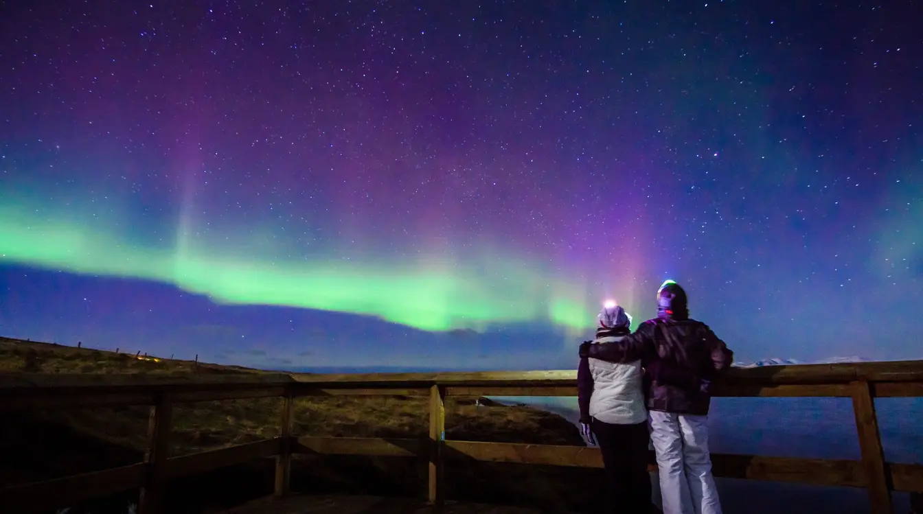Couple observant une aurore boréale dans le ciel nocturne en Islande.
