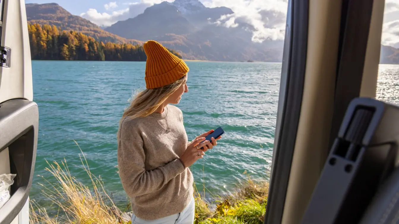Femme utilisant son téléphone portable au bord d'un lac de montagne en Suisse.
