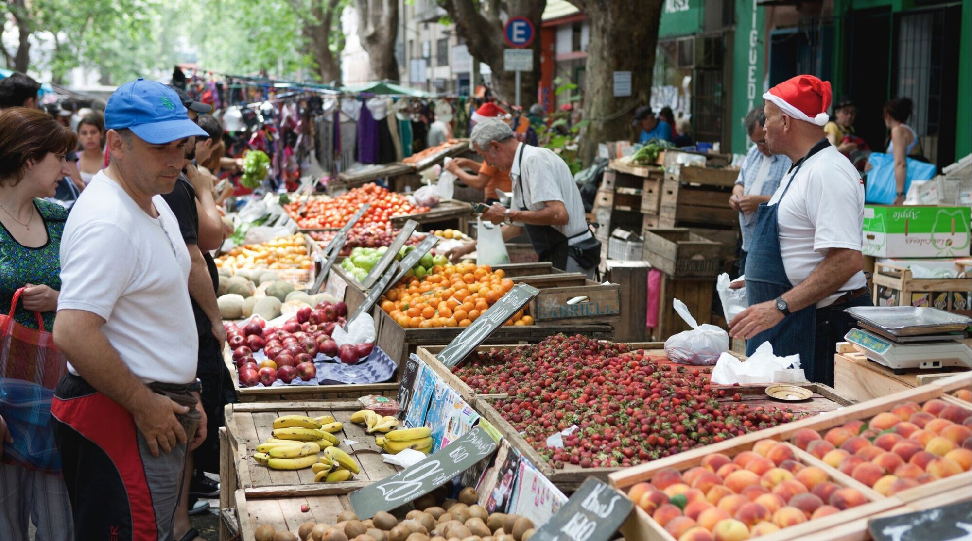 À medida que o Natal se aproxima, os trabalhadores das barracas do mercado usam gorros festivos de Natal enquanto vendem suas frutas e verduras aos clientes.