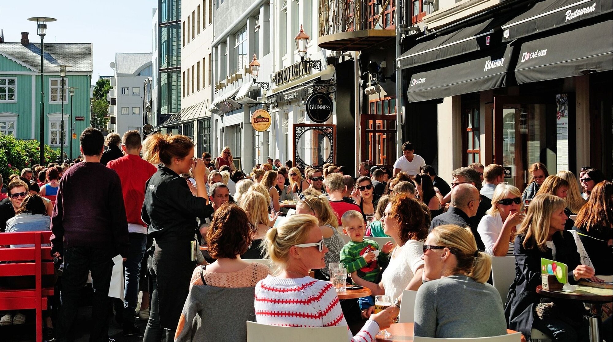 Islandeses curtindo o bom tempo em um café ao ar livre no centro de Reykjavik