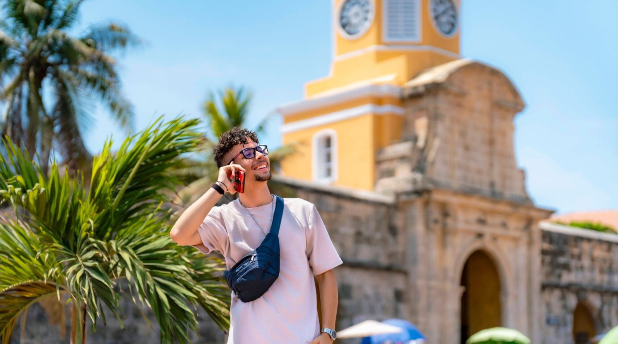 Hombre joven sonriendo mientras habla por teléfono en una calle de Cartagena, Colombia.