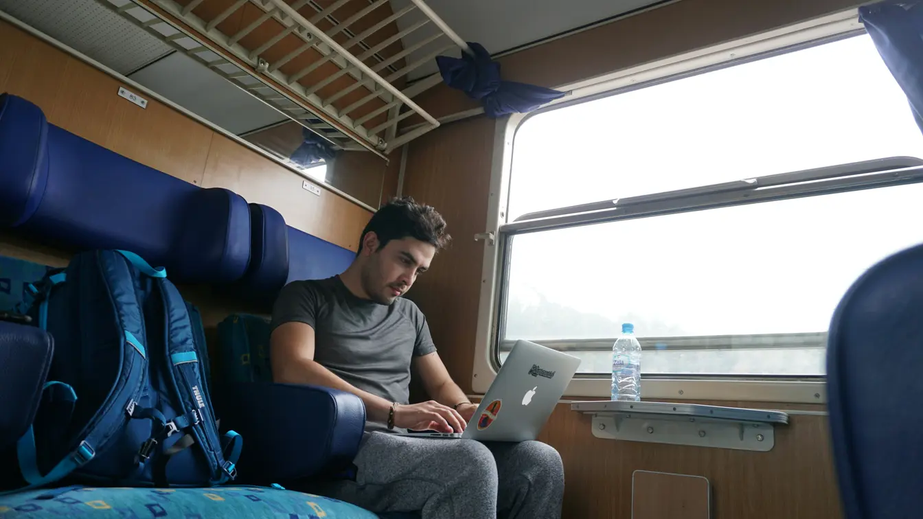 Imagen de una persona trabajando en su portátil en un tren, para ilustrar los nómadas digitales que teletrabajan desde cualquier parte.