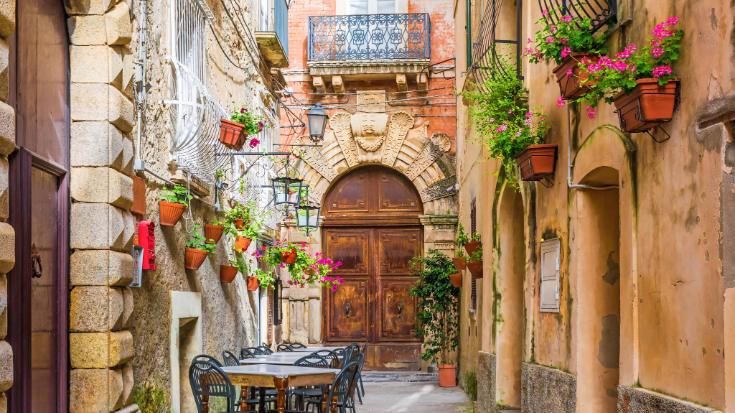 A colour photo of the village of Positano, showing pastel-coloured houses in shades of peach, pink, and terracotta.