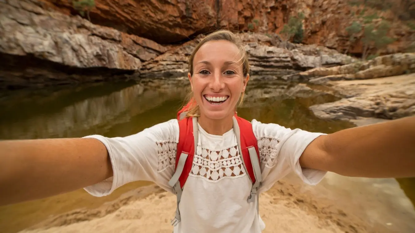 Randonneuse prenant un selfie au milieu d’un paysage naturel en Australie.