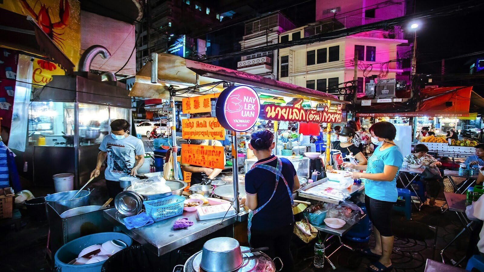 Street food vendors in their stalls, preparing and selling food at night