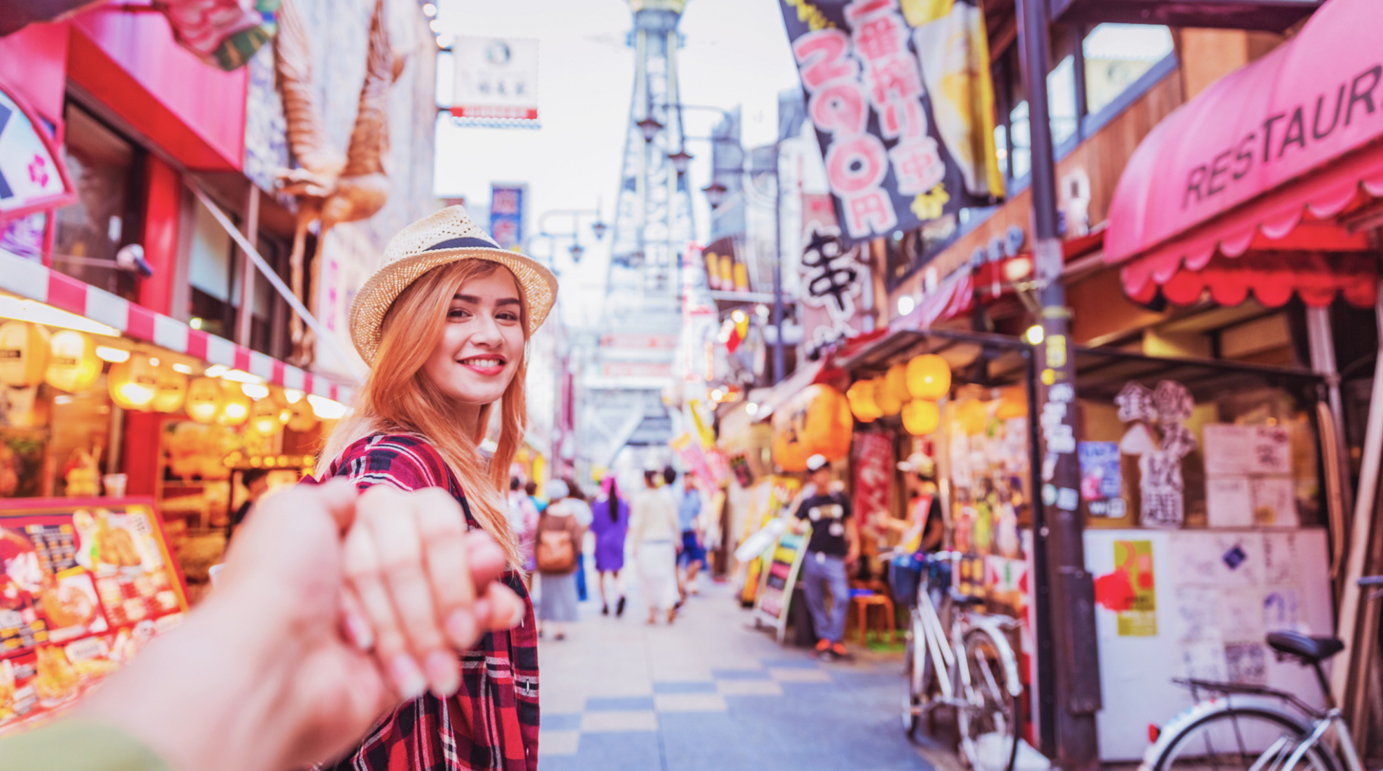 Coppia che esplora le strade di Shinsekai a Osaka usando lo smartphone per orientarsi e avere internet in Giappone